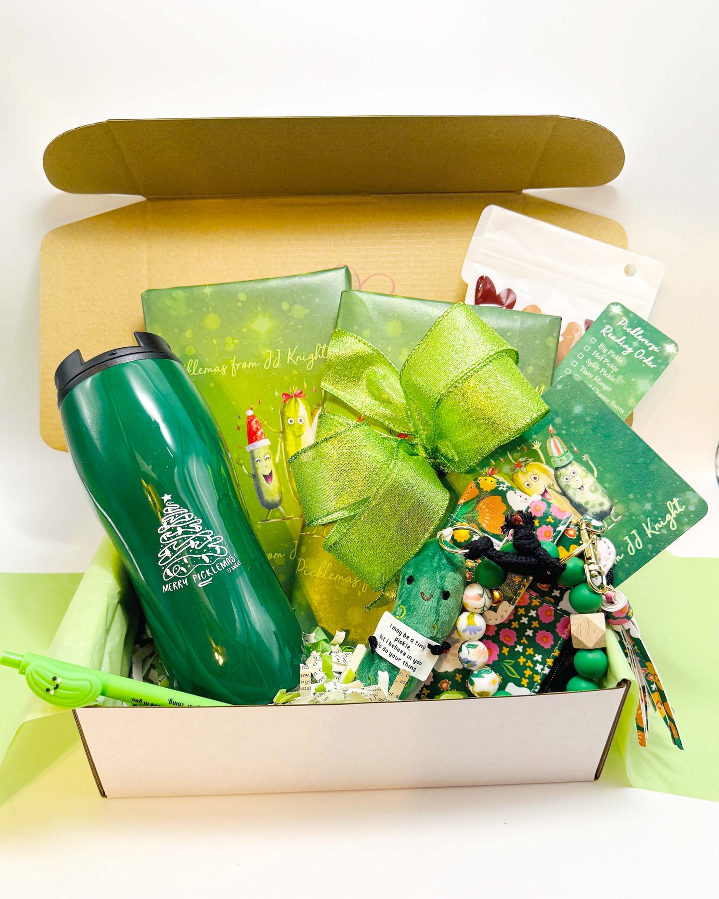 Christmas Pickle gift box with green ribbon, Santa Claus-themed item, mug and decorative items with wrapped romantic comedy books