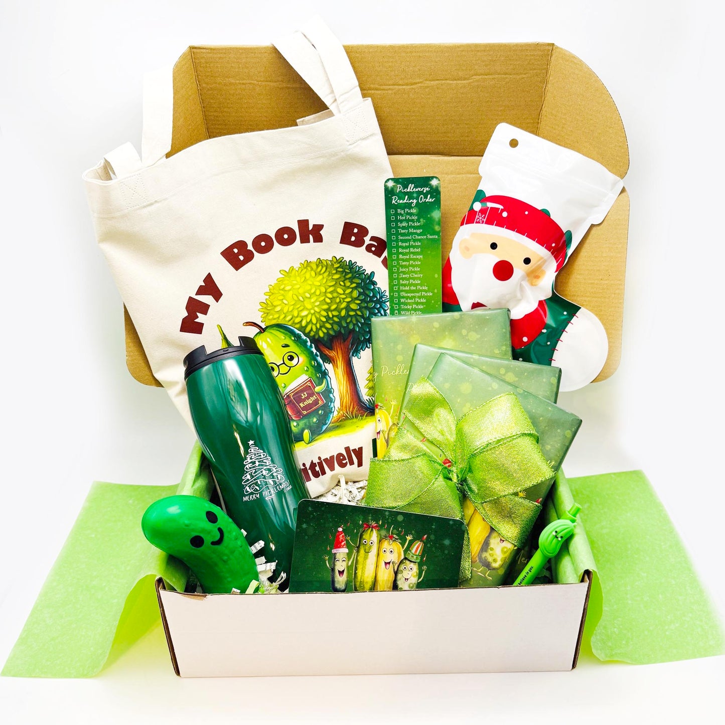 Christmas Pickle gift box with green ribbon, tote bag, Santa Claus-themed item, mug and decorative items with wrapped romantic comedy books
