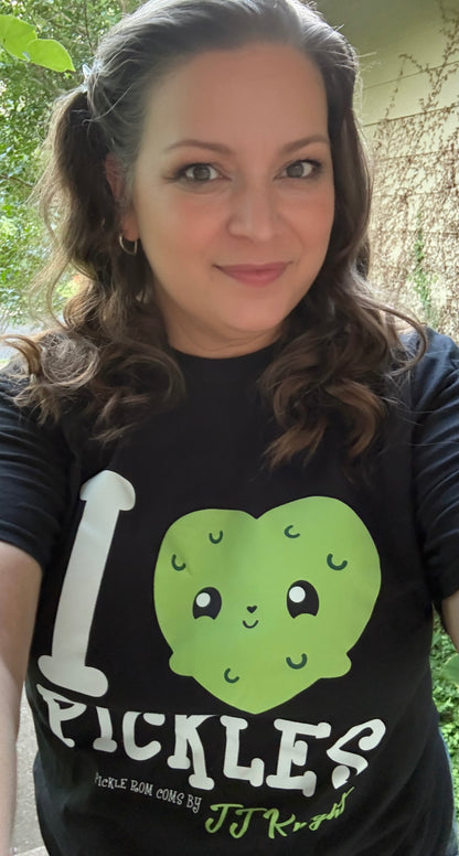 Person wearing a black t-shirt with a green pickle graphic and text outdoors.