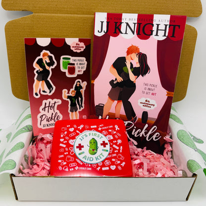A curated gift box set featuring a copy of the book 'Hot Pickle' by JJ Knight, a red 'First Aid Kit' box, and matching stickers.