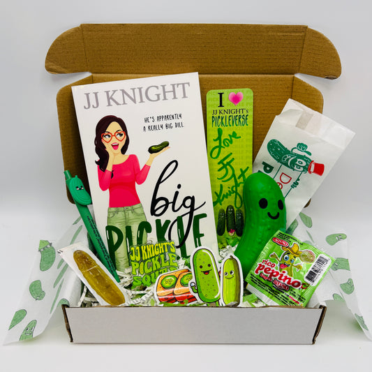 JJ Knight pickle-themed product set including a full length romantic comedy paperback, a stress pickle, keychain, stickers, and packaging 