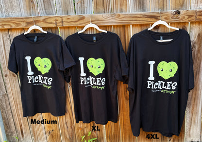 Three black t-shirts with 'I ❤️ Pickles' design on hangers against a wooden fence.